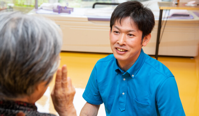 入居者さまと秋桜の介護職員がお話をしている様子