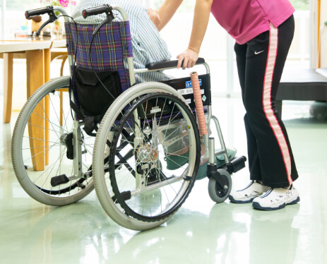 秋桜の介護職員が車椅子に乗る利用者さまをサポートしている様子
